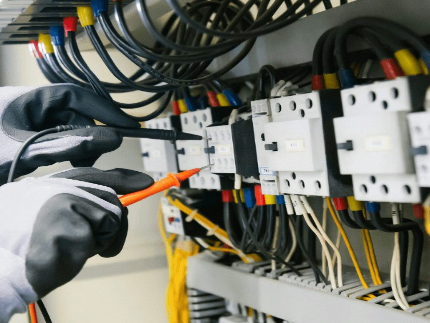 Mains d'électricien testant un tableau électrique au multimètre