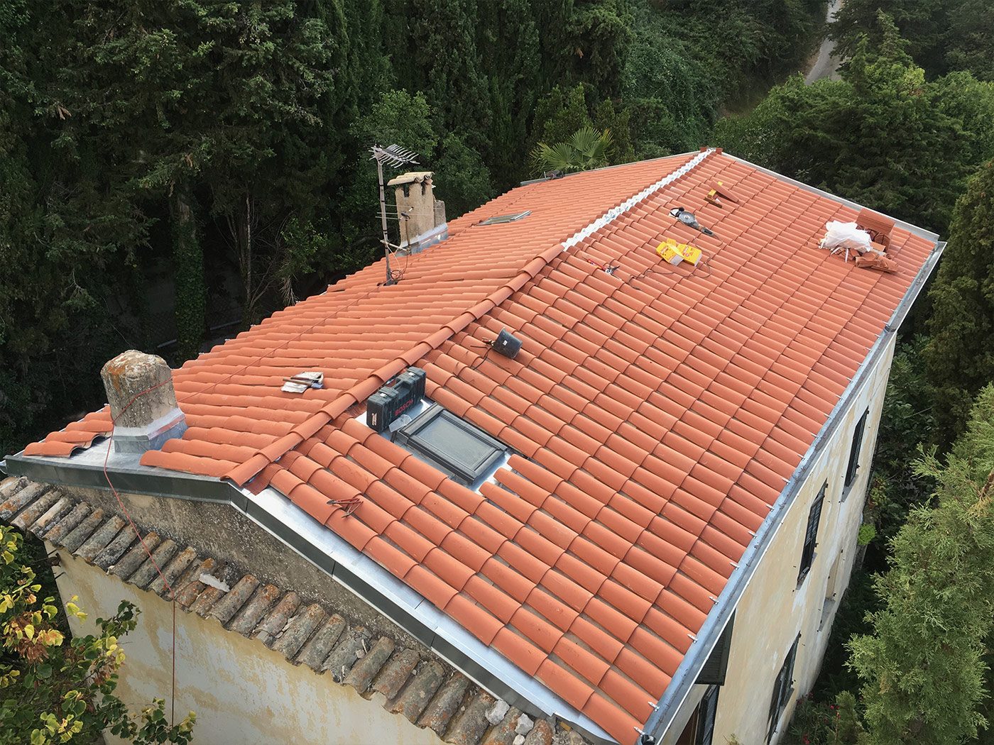 Couvreur posant des tuiles terre cuite sur un toit, ciel en arrière-plan